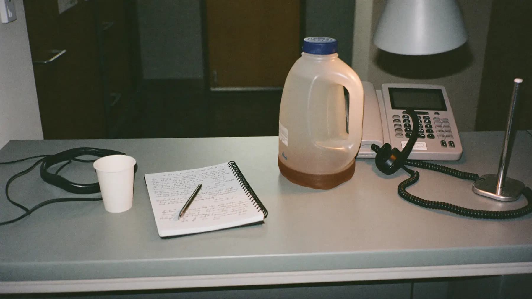 An event helpdesk counter mid-shift: a headset on a coiled cord, a desk phone and a well-used notebook.